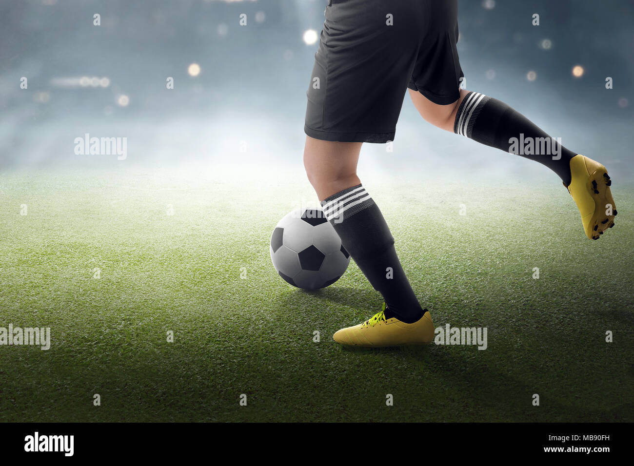 Giocatore di calcio cercando di calciare la palla sul campo in erba Foto Stock