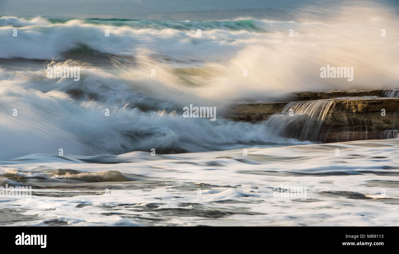 Spiaggia rocciosa con oceano ondulato vento e onde che si infrangono sulle rocce al Akrotiri area costiera in Limassol, Cipro Foto Stock