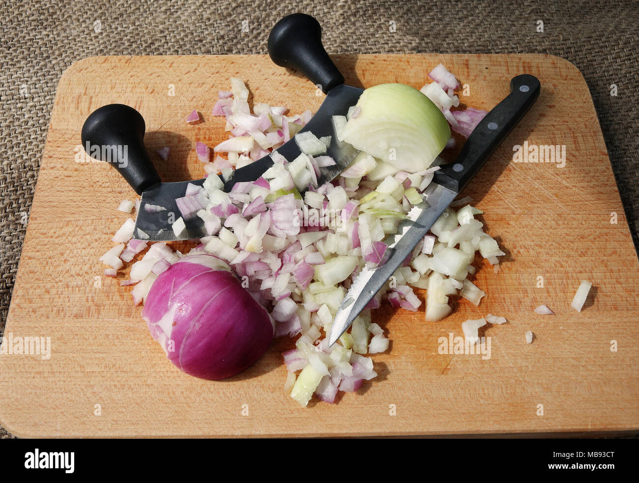 Tagliere di legno con il rosso e bianco cipolle, un coltello per affettare e utensile Foto Stock