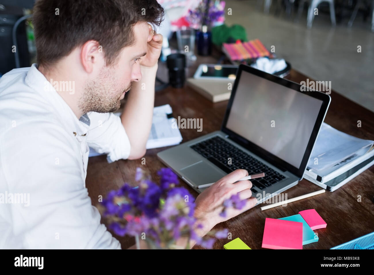Uomo caucasico lavorando sul computer portatile mentre è seduto al suo ufficio moderno posto. Concetto di giovani usando coworking posto. Foto Stock