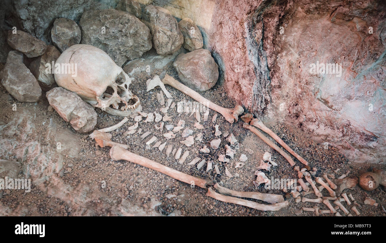 Il teschio e ossa di un uomo primitivo all'interno di una grotta. Foto Stock