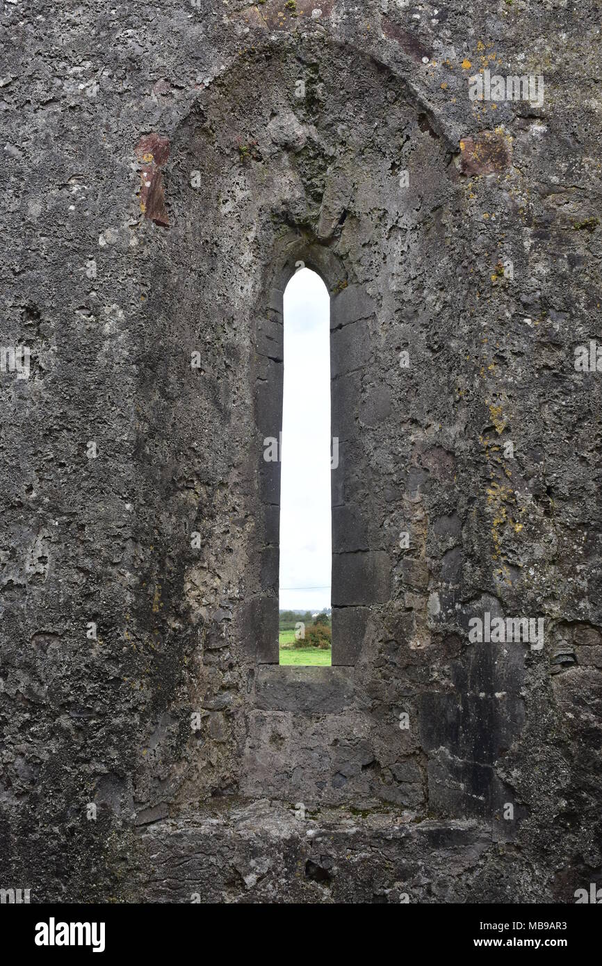 Stretta finestra medievale in pietra dello spessore di parete di rovine di Clare Abbey in Irlanda. Foto Stock