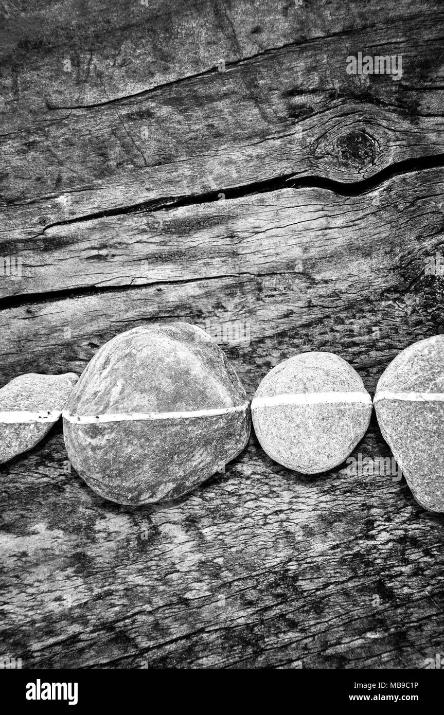 Fila di pietre su un sfondo di legno, in bianco e nero Foto Stock