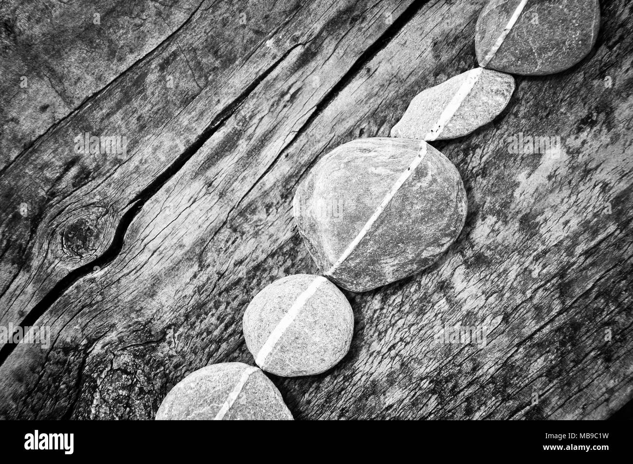 Fila di pietre su un sfondo di legno, in bianco e nero Foto Stock