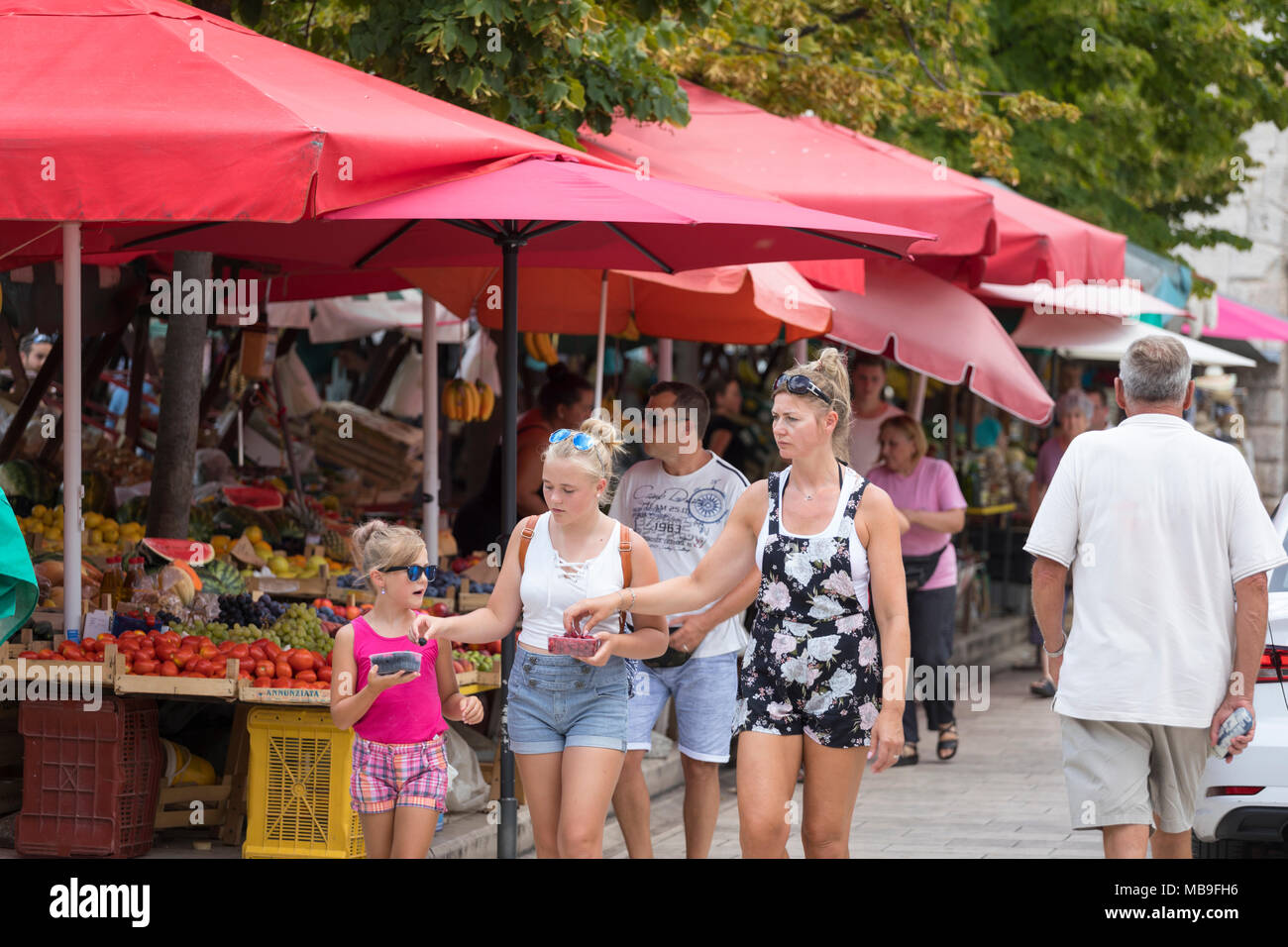 La madre e le sue due figlie di mangiare i frutti di bosco al mercato di Zadar, Croazia Foto Stock