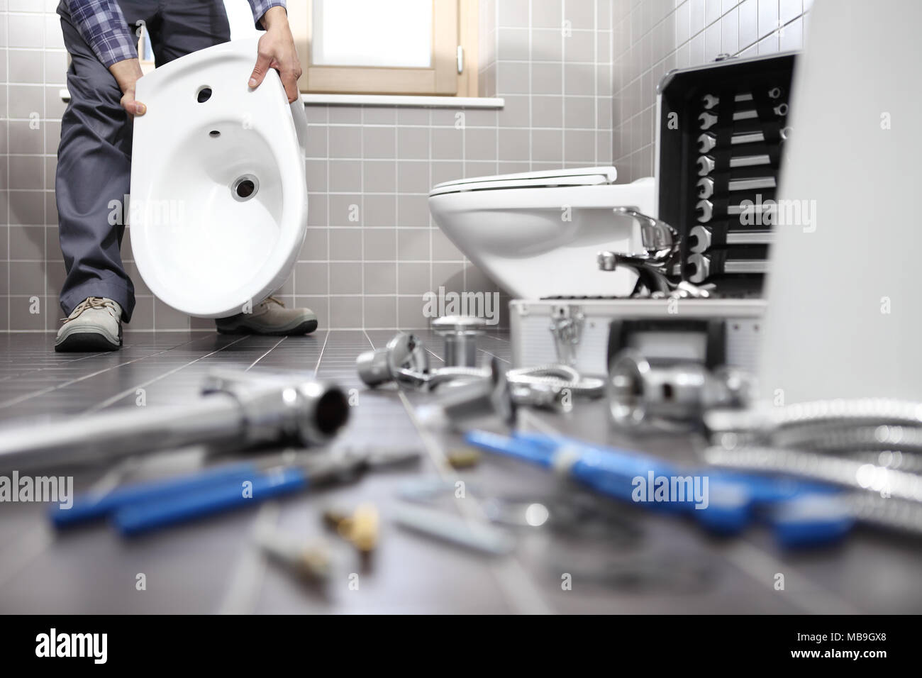 Plumber al lavoro in un bagno, idrosanitari servizio di riparazione, assemblare e installare il concetto Foto Stock