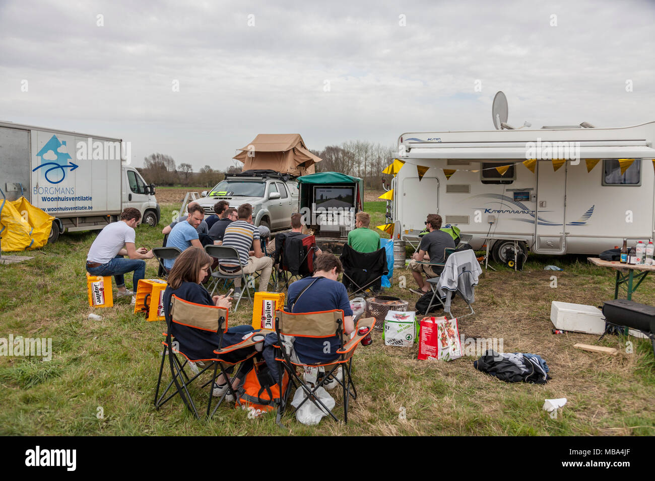 Templeuve, Francia - Aprile 08, 2018: gruppo di spettatori all'aperto sul ciglio della strada a guardare sulla TV la gara live broadcast in Templeuve durante Paris-Roubaix 2018. Credito: Radu Razvan/Alamy Live News Foto Stock