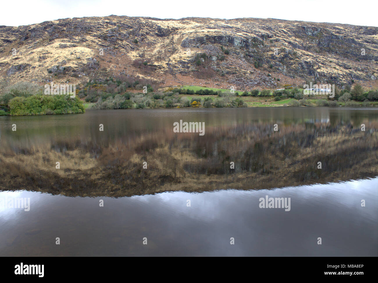 Le colline intorno al lago di Gougane Barra, Irlanda riflette nella ancora acque scure del lago. Una meta turistica molto e per vacanza destinazione. Foto Stock