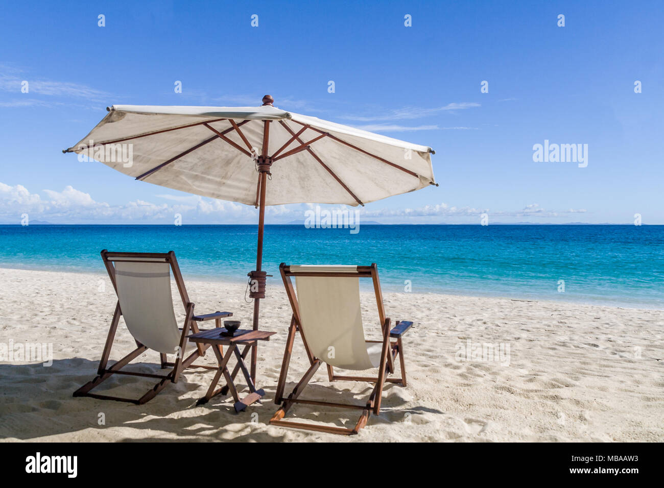 Lettini per prendere il sole sulla spiaggia di sabbia bianca di fronte alla laguna Foto Stock