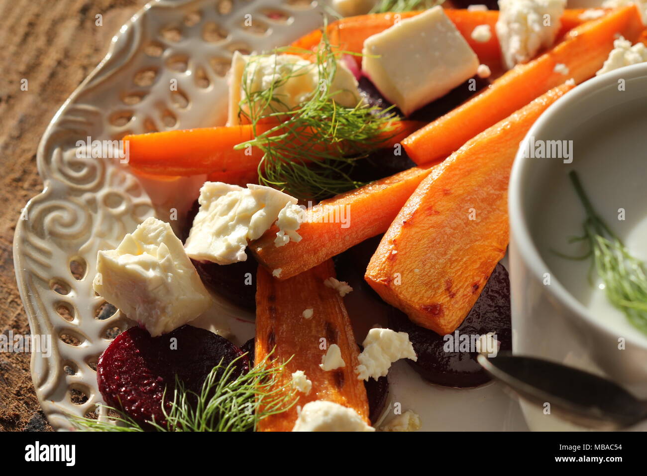 Una sana grigliate di barbabietole e carote Insalata con formaggio feta, finocchio e lo yogurt greco in piccole ciotole in vetro sulla tavola in legno rustico, vista dall'alto Foto Stock