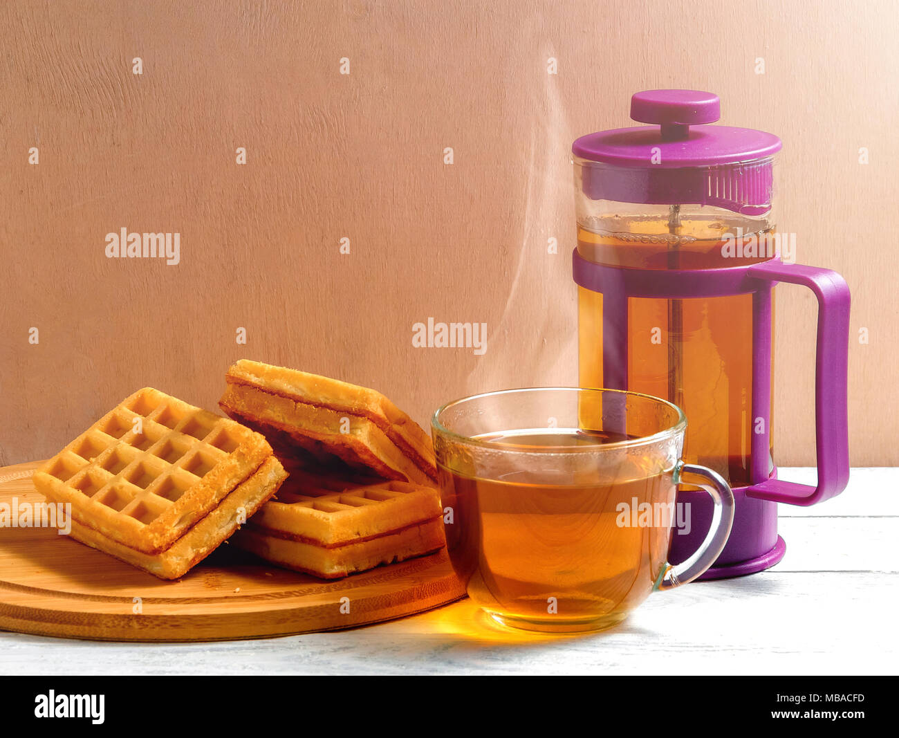 Waffles fatti in casa con la marmellata sul vecchio tavolo in legno. Wafers con tazza di tè e teiera. Foto Stock