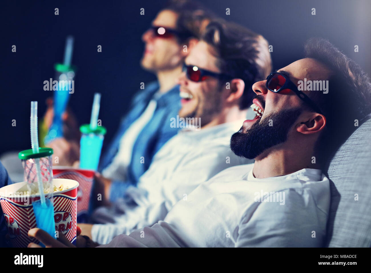 Gruppo di happy amici seduti nel cinema guardare film e mangiare popcorn Foto Stock