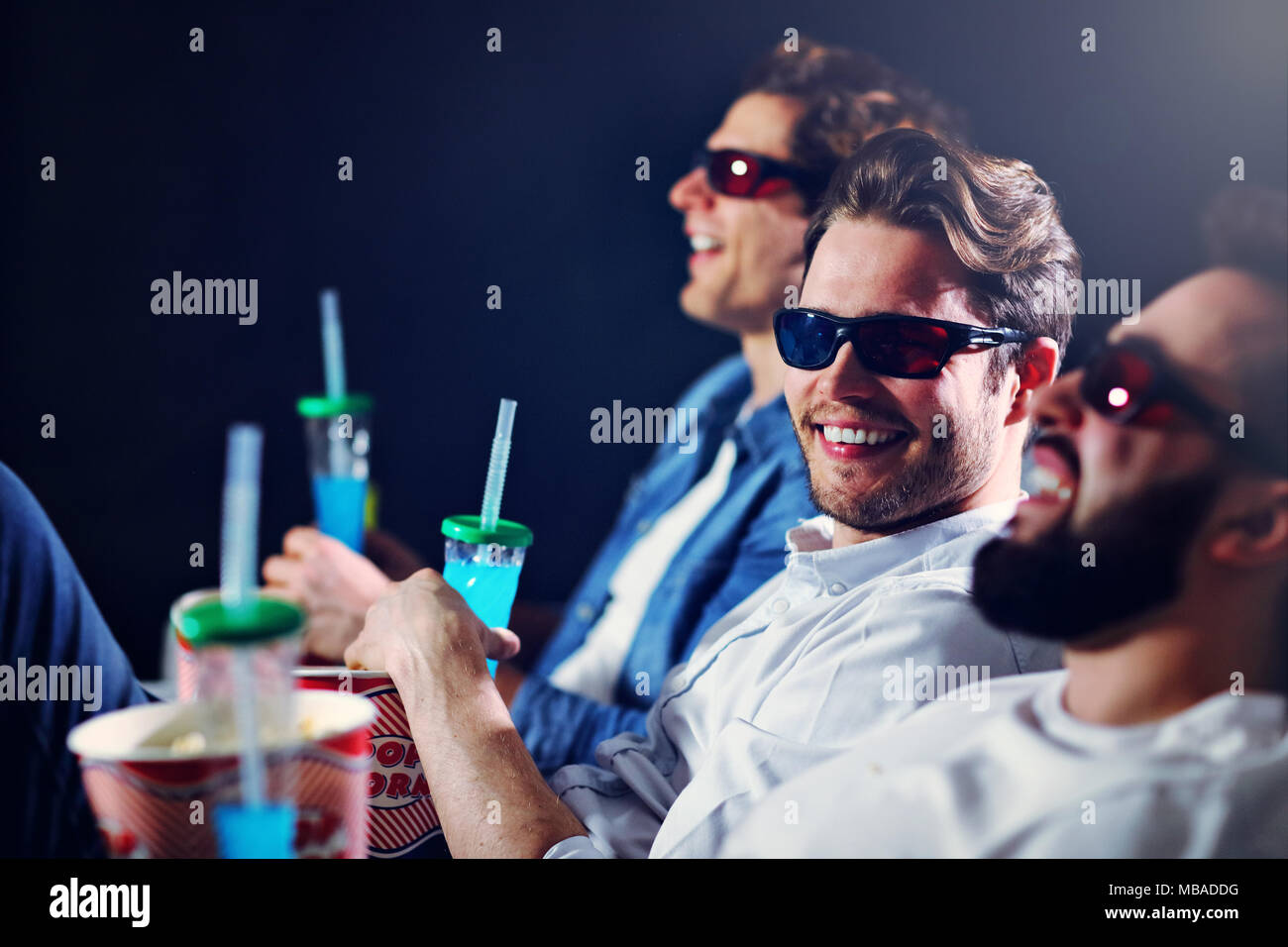 Gruppo di happy amici seduti nel cinema guardare film e mangiare popcorn Foto Stock