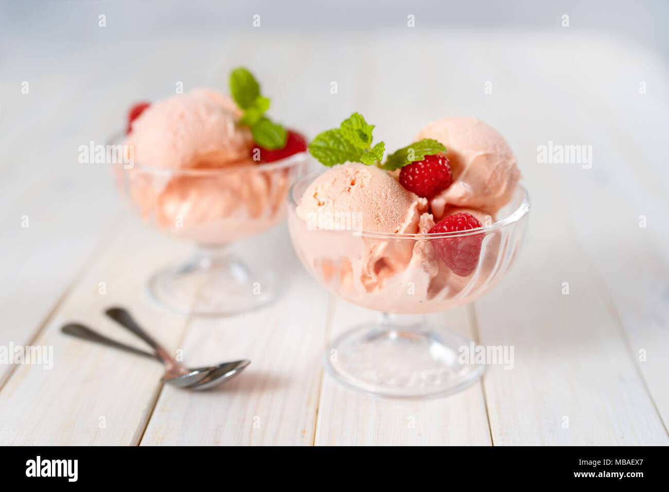 Studio shot del gelato al lampone in piatti in vetro bianco sul tavolo di legno Foto Stock