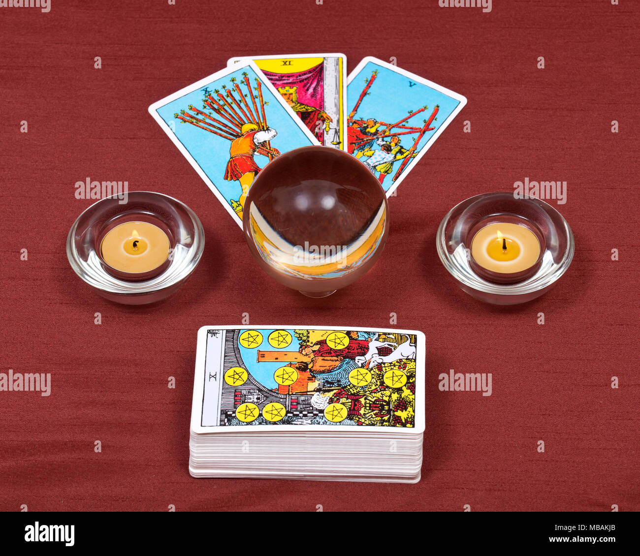 Rider Waite tarocchi, sfera di cristallo e candele accese sul tessuto rosso sfondo Foto Stock