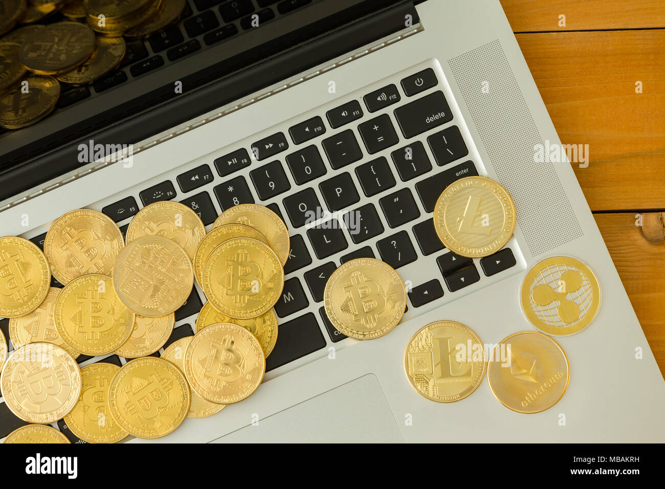 Le monete d'oro di cryptocurrencies, Bitcoin, Ethereum e Litecoin, sparsi su tastiera portatile, visto dal di sopra in close-up Foto Stock