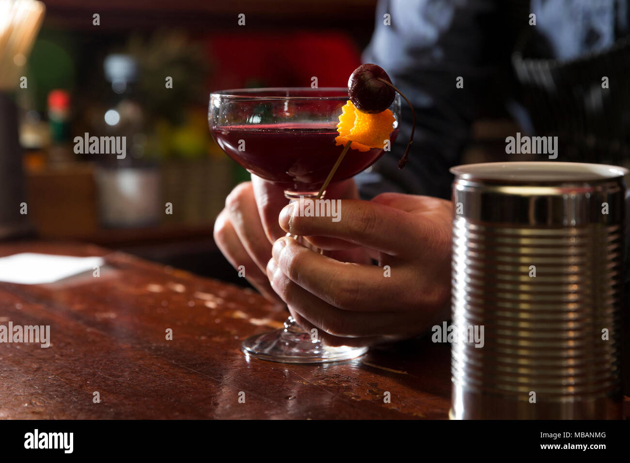 Primo piano di un barman decorare con una ciliegina vodka sour sulla barra di legno counter Foto Stock