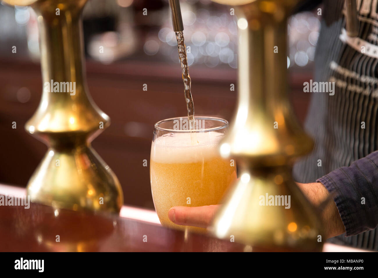 Primo piano di un barman versando una birra bionda in tap Foto Stock