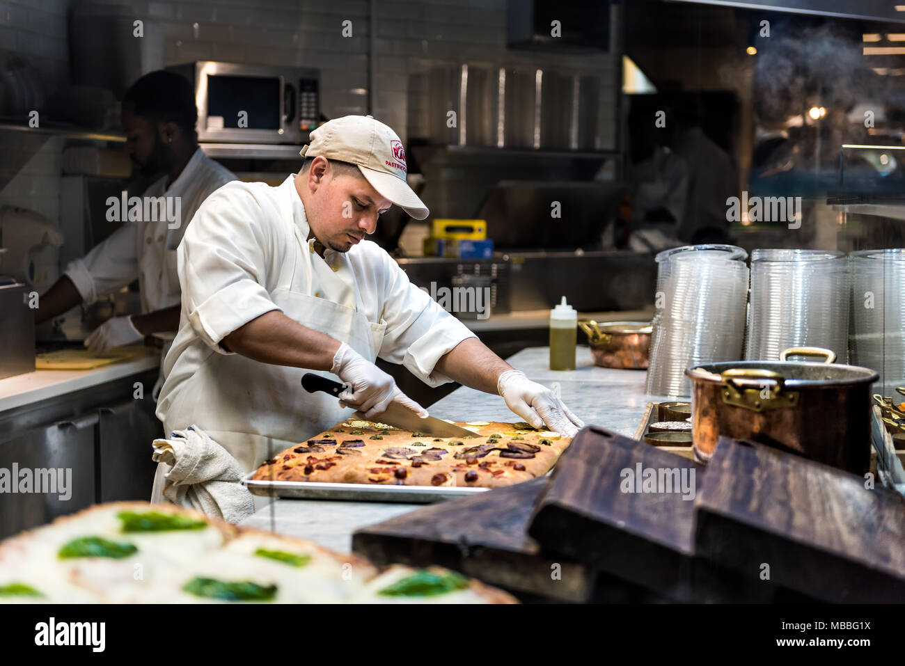 La città di New York, Stati Uniti d'America - 30 Ottobre 2017: uomo chef foccacia di taglio il pane cotto nel forno di rana ristorante di cucina nel mercato Chelsea Foto Stock