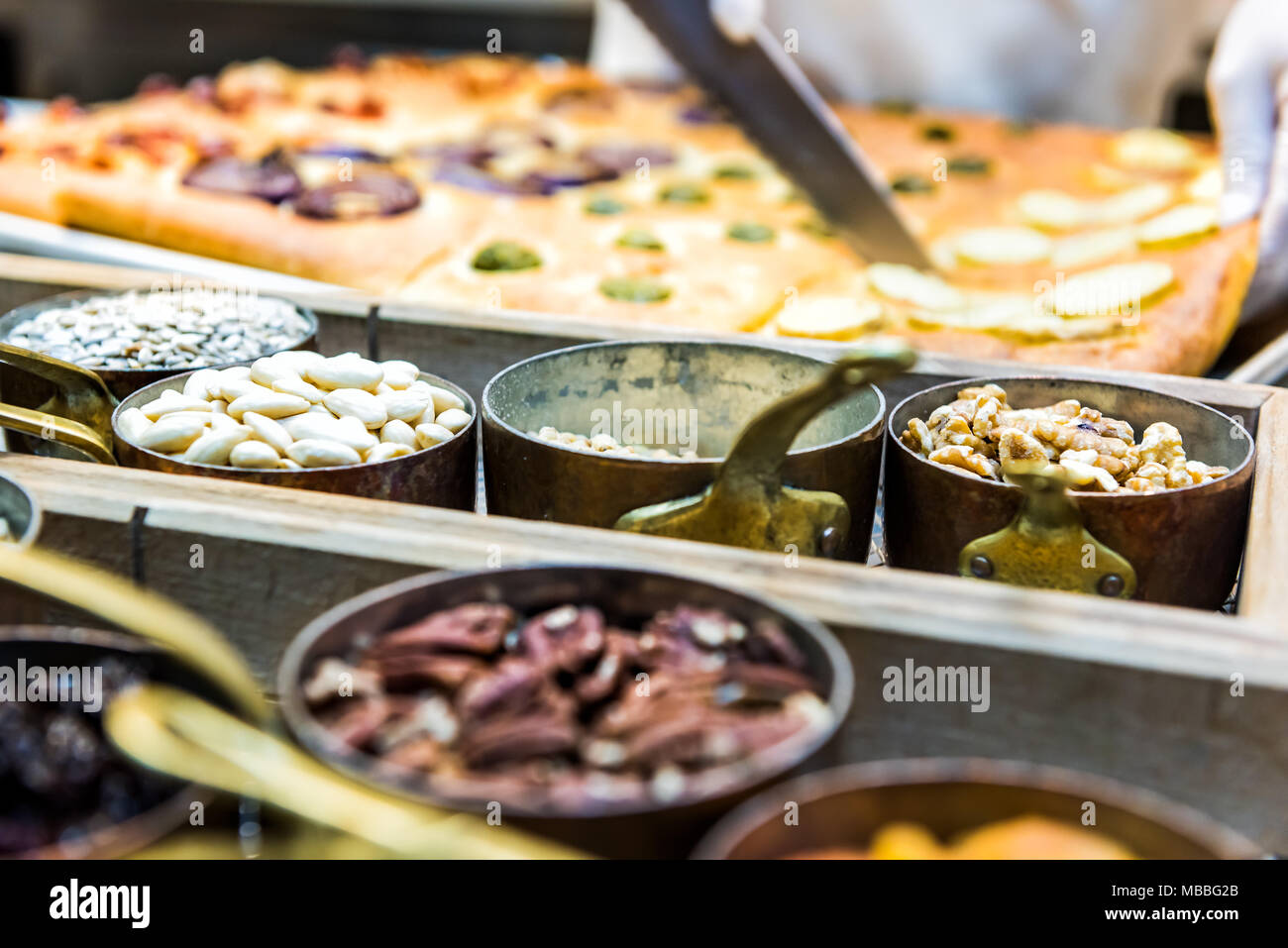 Il taglio foccacia pane con coltello, noci, spezie in contenitori e condimenti cotto in forno, lo chef del ristorante cucina Foto Stock