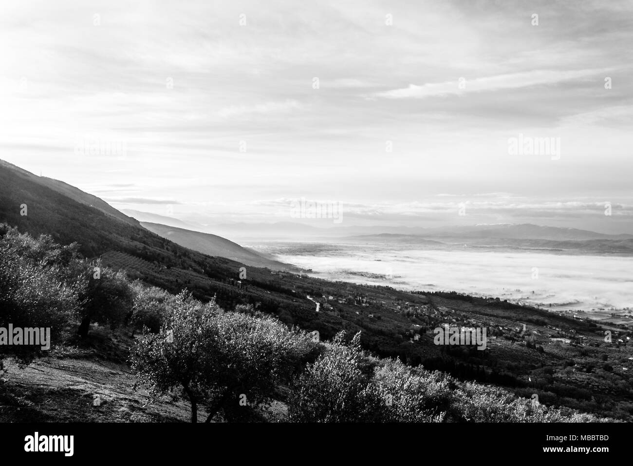 Splendida vista della valle umbra in un inverno mattina, con la nebbia che copre gli alberi e le case Foto Stock
