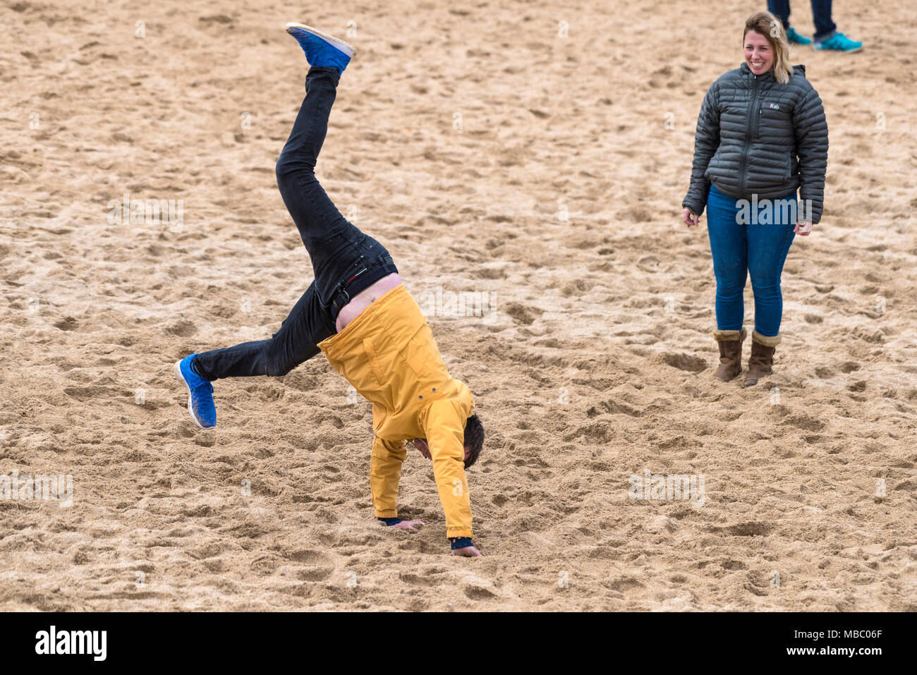 Un uomo che tenta di eseguire un appoggiate su Fistral Beach in Newquay Cornwall. Foto Stock