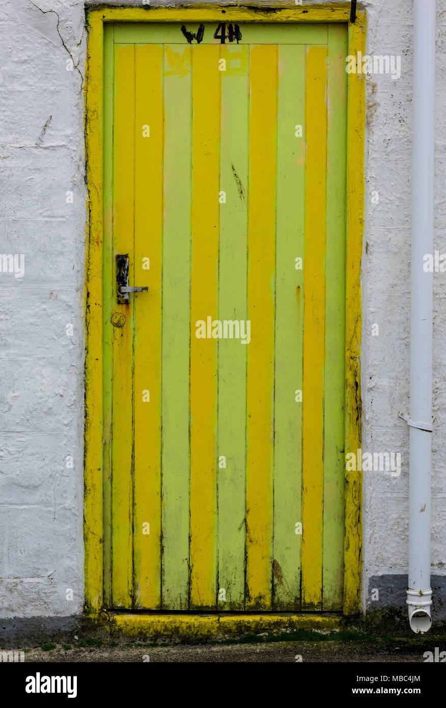Un dipinto luminosamente giallo e verde porta stripey nel villaggio di pescatori di St Ives in Cornovaglia occidentale. Vivacemente colorato di ingresso o porta ingresso. Foto Stock