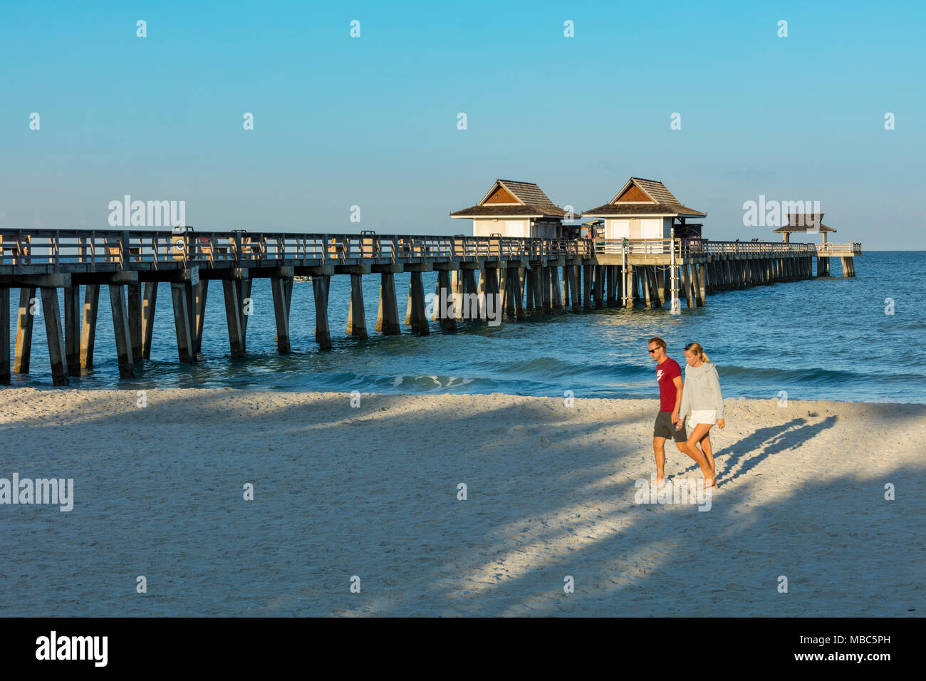 Giovane camminando lungo la spiaggia la mattina presto a Napoli molo lungo la costa del Golfo della Florida, Naples, Florida, Stati Uniti d'America Foto Stock