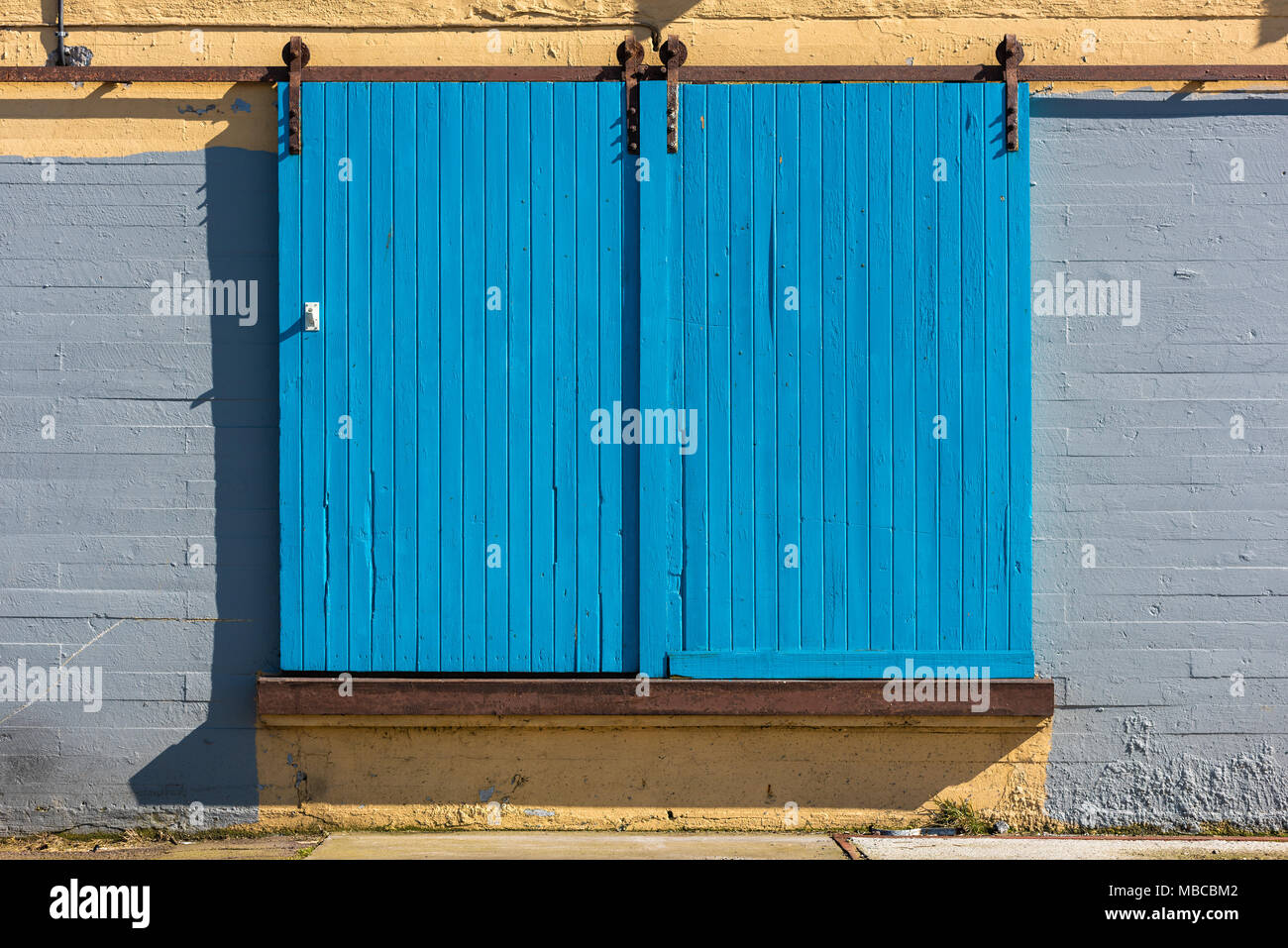 In legno di colore blu porte scorrevoli su edificio industriale. Foto Stock