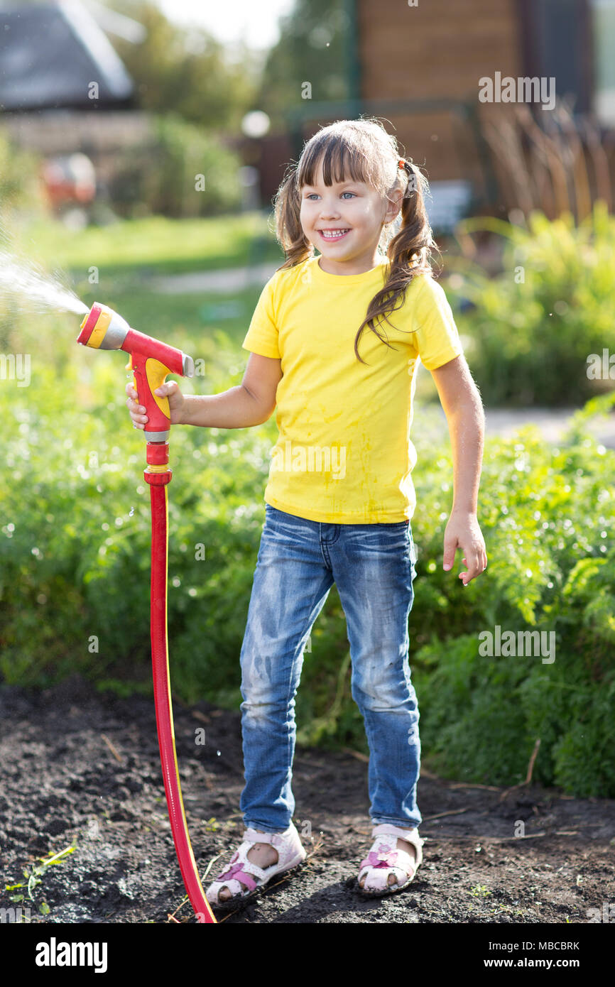 Piccolo giardiniere irrigazione ragazza con tubo flessibile Foto Stock