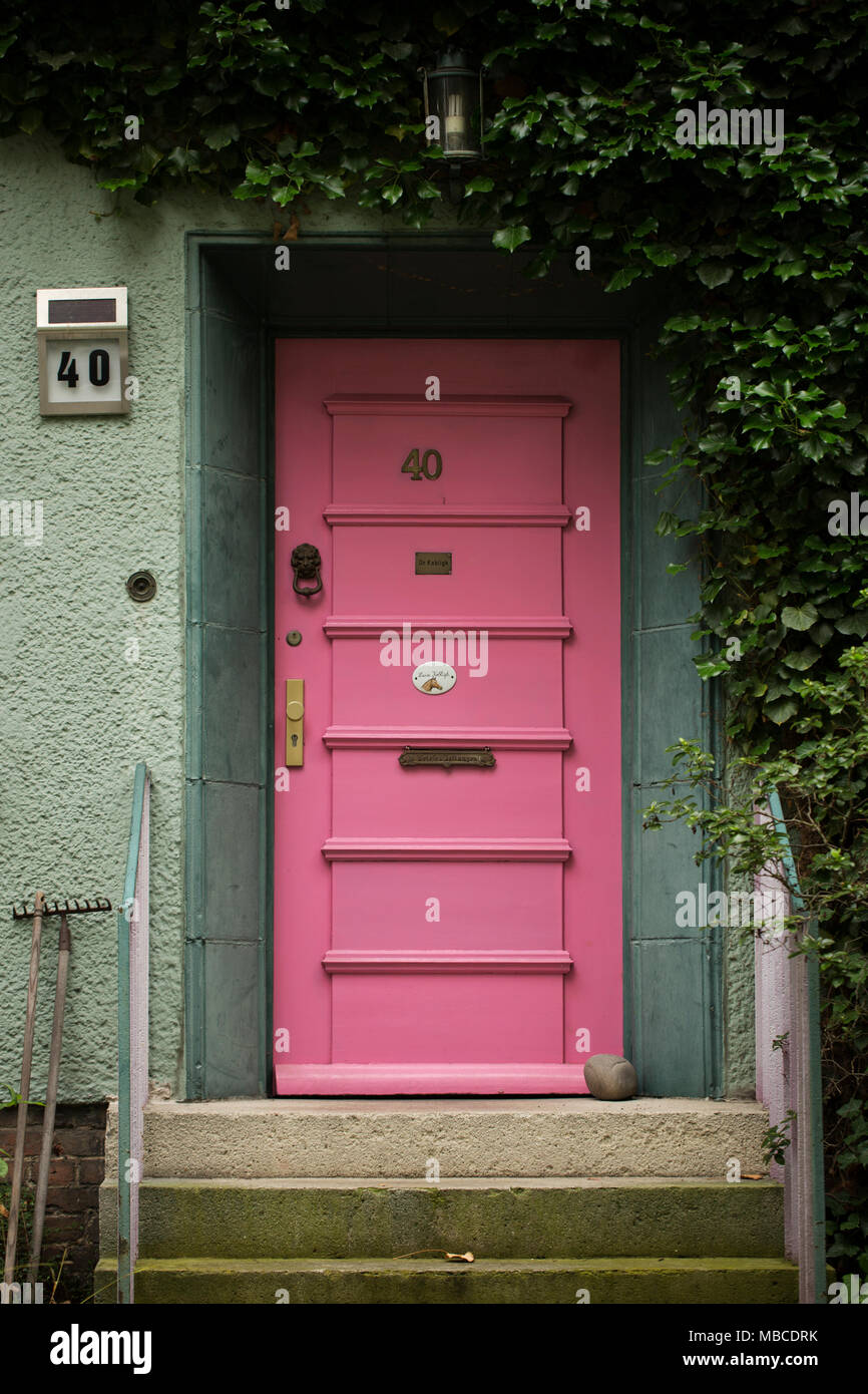 Una porta rosa su una casa verde di edera arrampicata le pareti, nel quartiere Steglitz di Berlino, Germania. Foto Stock
