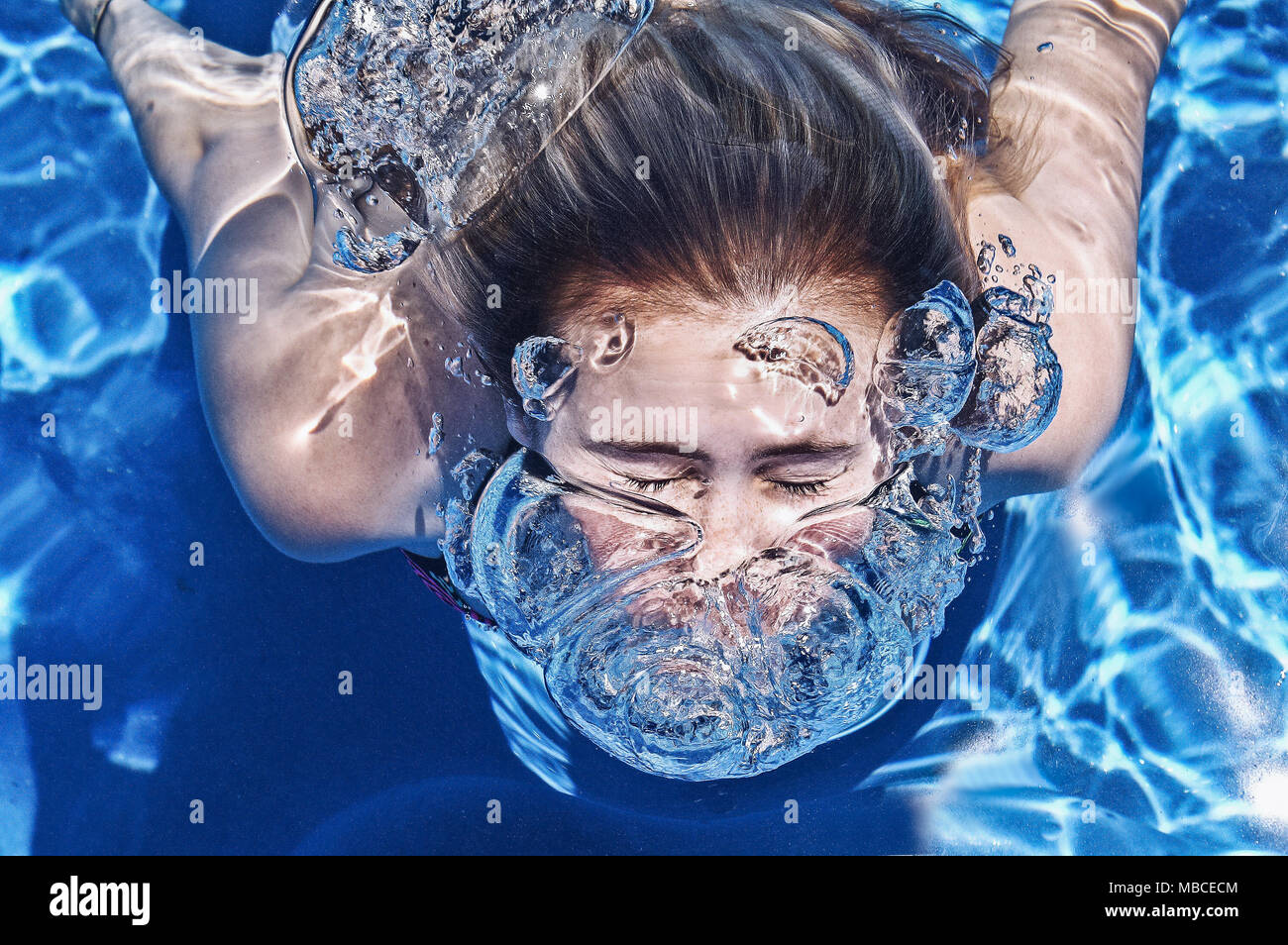 Giovane donna subacquea sommerso e soffiare bolle Foto Stock
