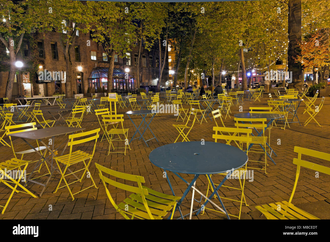 WA15078-00...WASHINGTON - tavolo e sedie nel luminoso Occidental Park di notte nel centro di Seattle. 2017 Foto Stock