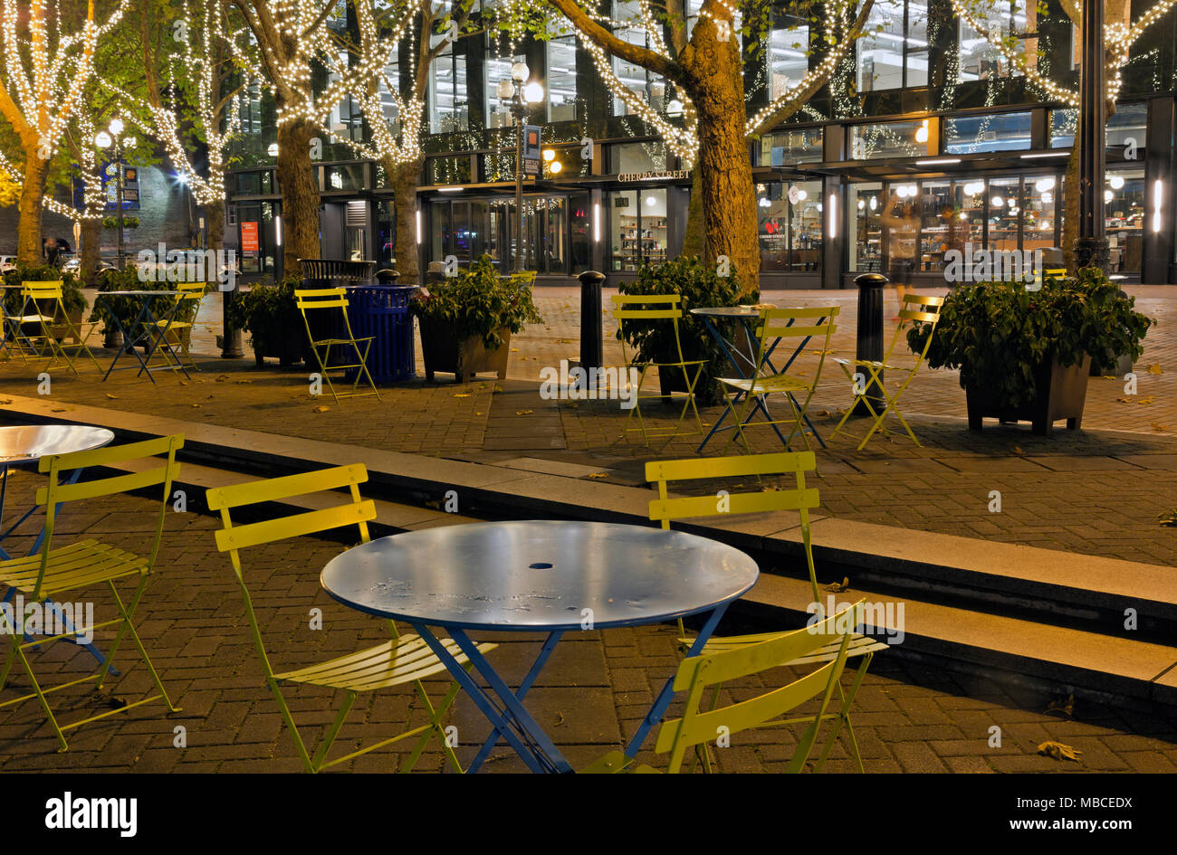 WA15079-00...WASHINGTON - tavolo e sedie nella luminosa Occidental parco di notte nel centro cittadino di Seattle. Foto Stock