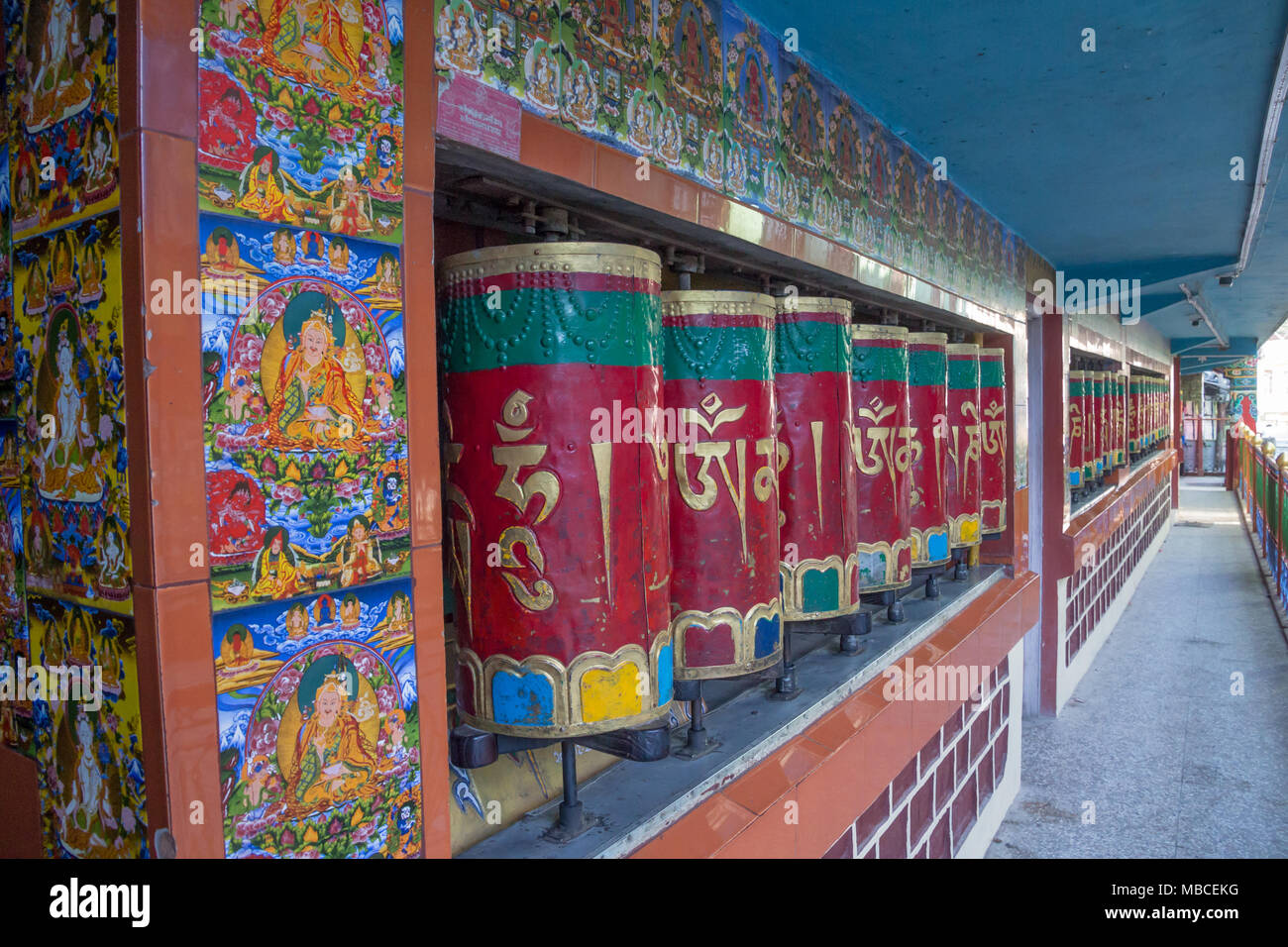 Schiacciata tra strade trafficate in McLeod Ganj (casa del Dalai Lama in esilio, questo tempio è decorato luminosamente esterno colorato con ruote della preghiera Foto Stock