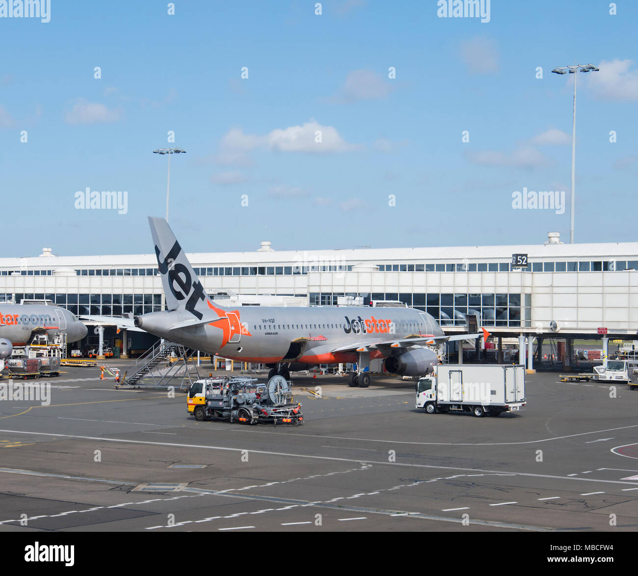 Il rifornimento di carrello e Gate Gourmet Catering Carrello su asfalto in prossimità di un Jetstar un aeromobile di tipo Airbus A320 all'Aeroporto di Sydney, terminale domestico, Australia Foto Stock