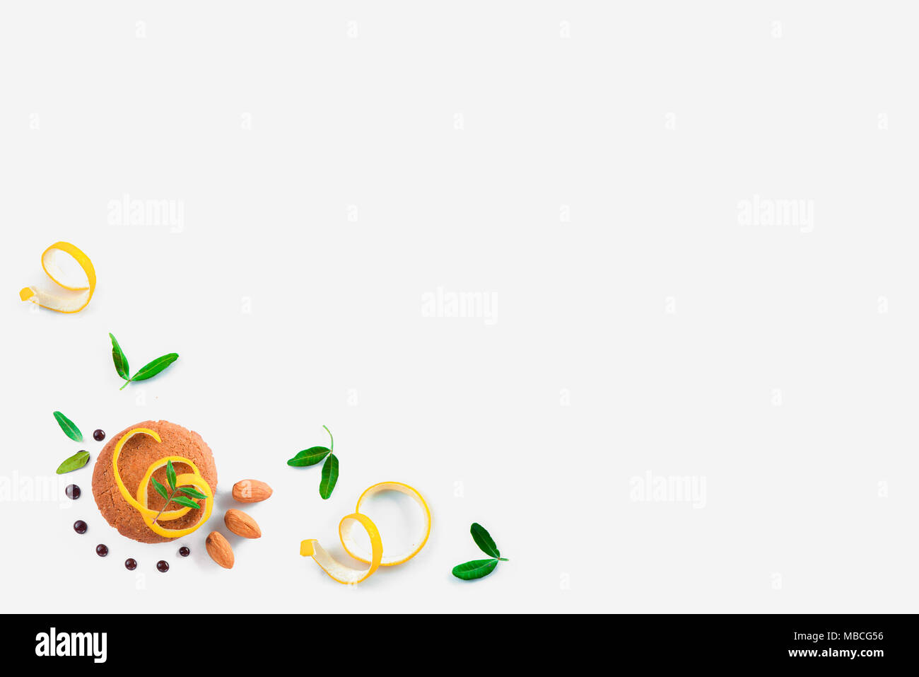Cookie decorate con la scorza di limone, mandorle e foglie verdi su sfondo bianco. Pasticceria Suggerimenti di stile concetto. Foto Stock