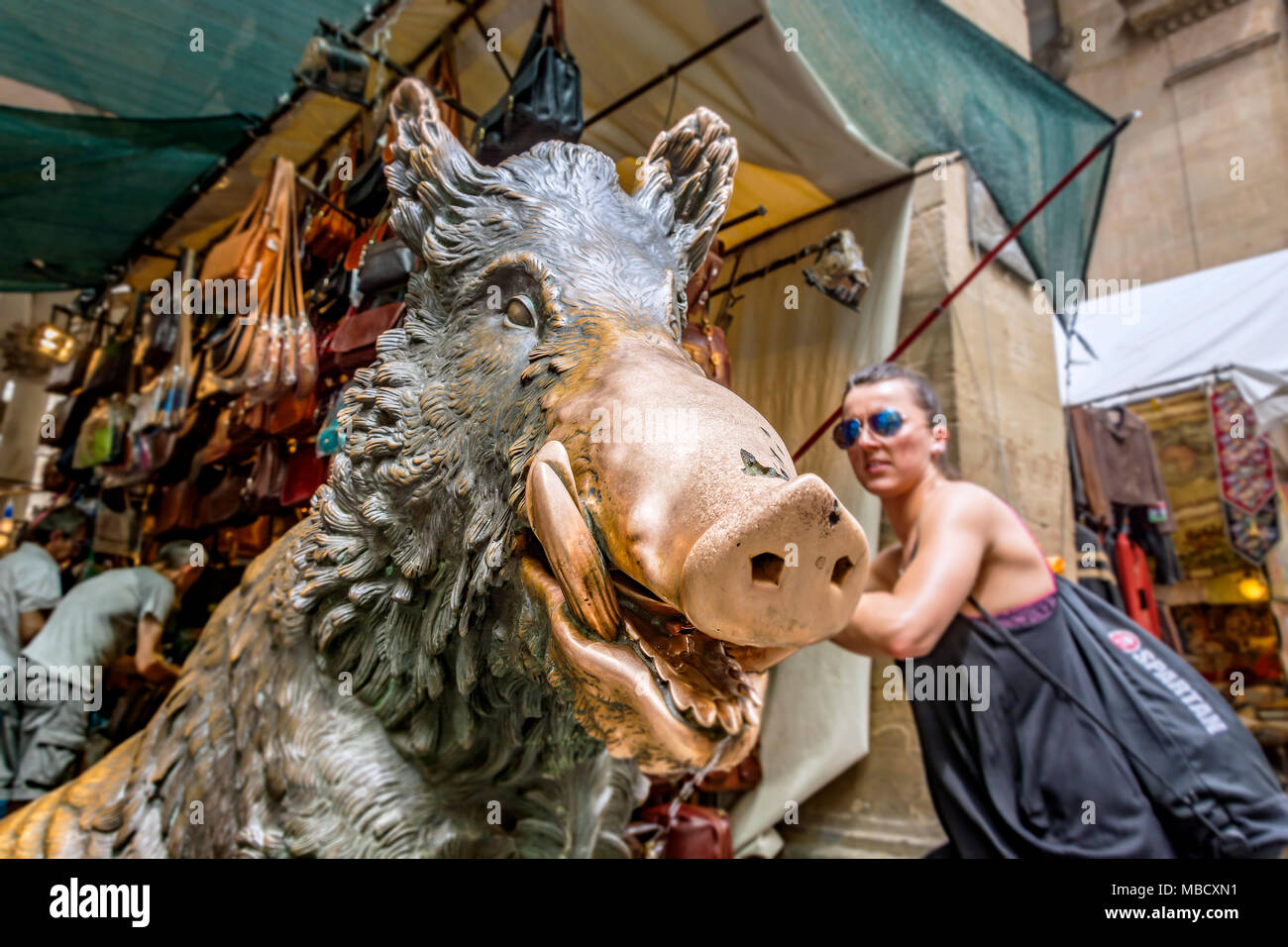 Firenze, Italia, Giugno 2015: Vista ravvicinata della famosa statua di bronzo di un cinghiale nel Mercato del Porcellino (maialino mercato) con un turista e alcuni Foto Stock