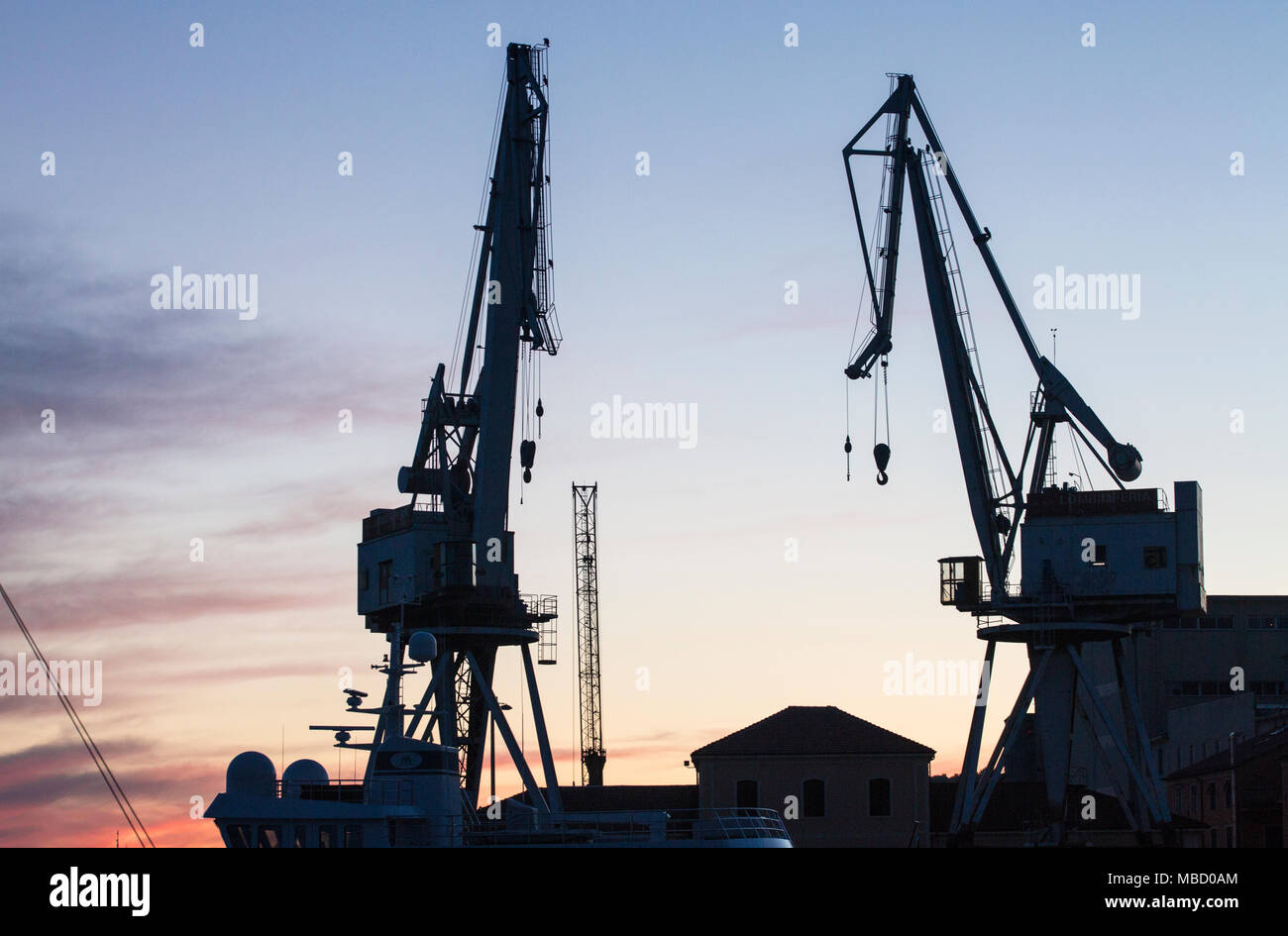 Le due gru nel porto di Oneglia fotografata dalla piattaforma al momento del tramonto Foto Stock