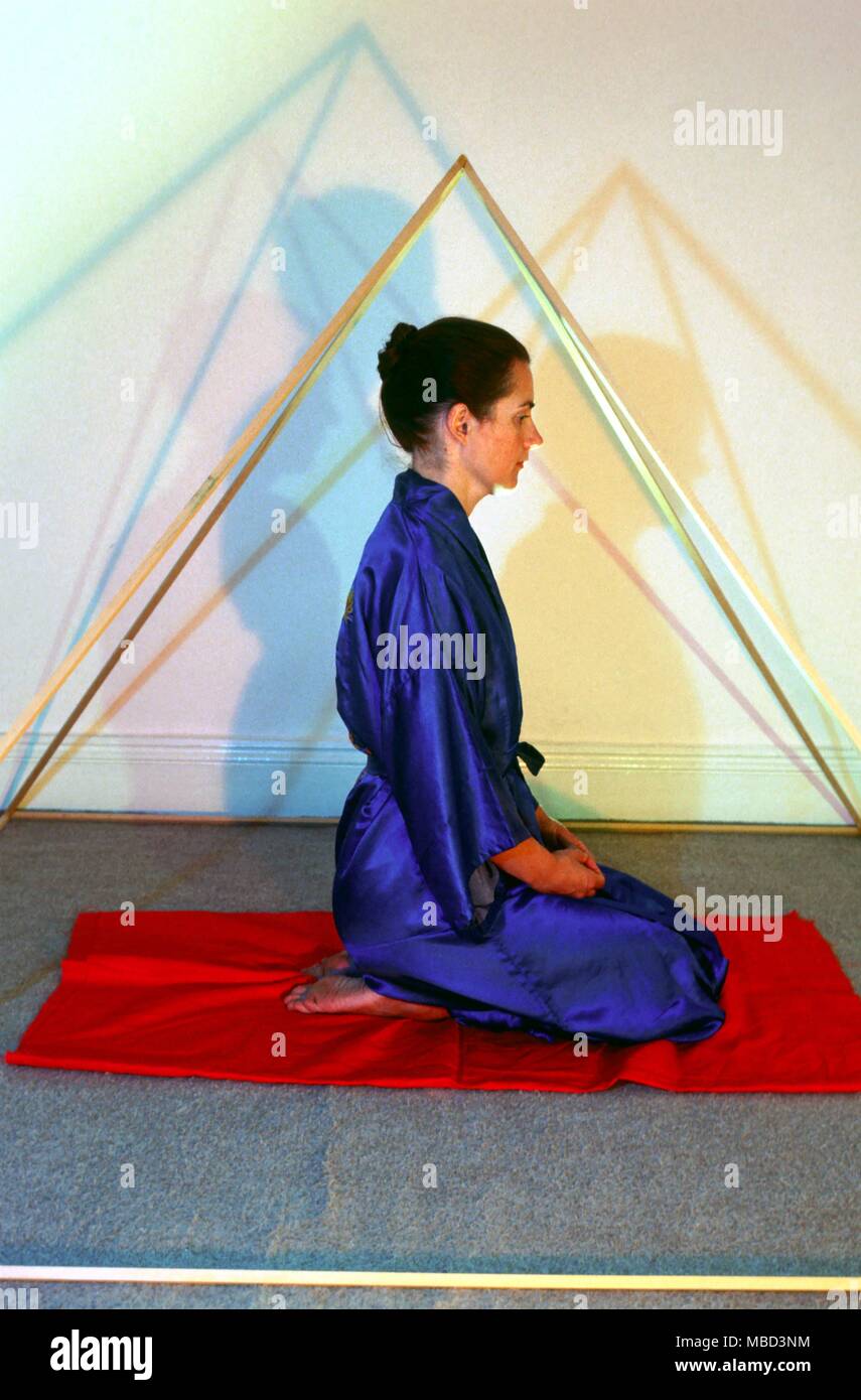 La meditazione ragazza meditando all'interno di un appositamente costruita a forma di piramide a realizzati in legno si è affermato che la meditazione è più facile in un tale spazio e che lo spazio stesso è in qualche modo la guarigione e favorevole alla mediazione Foto Stock