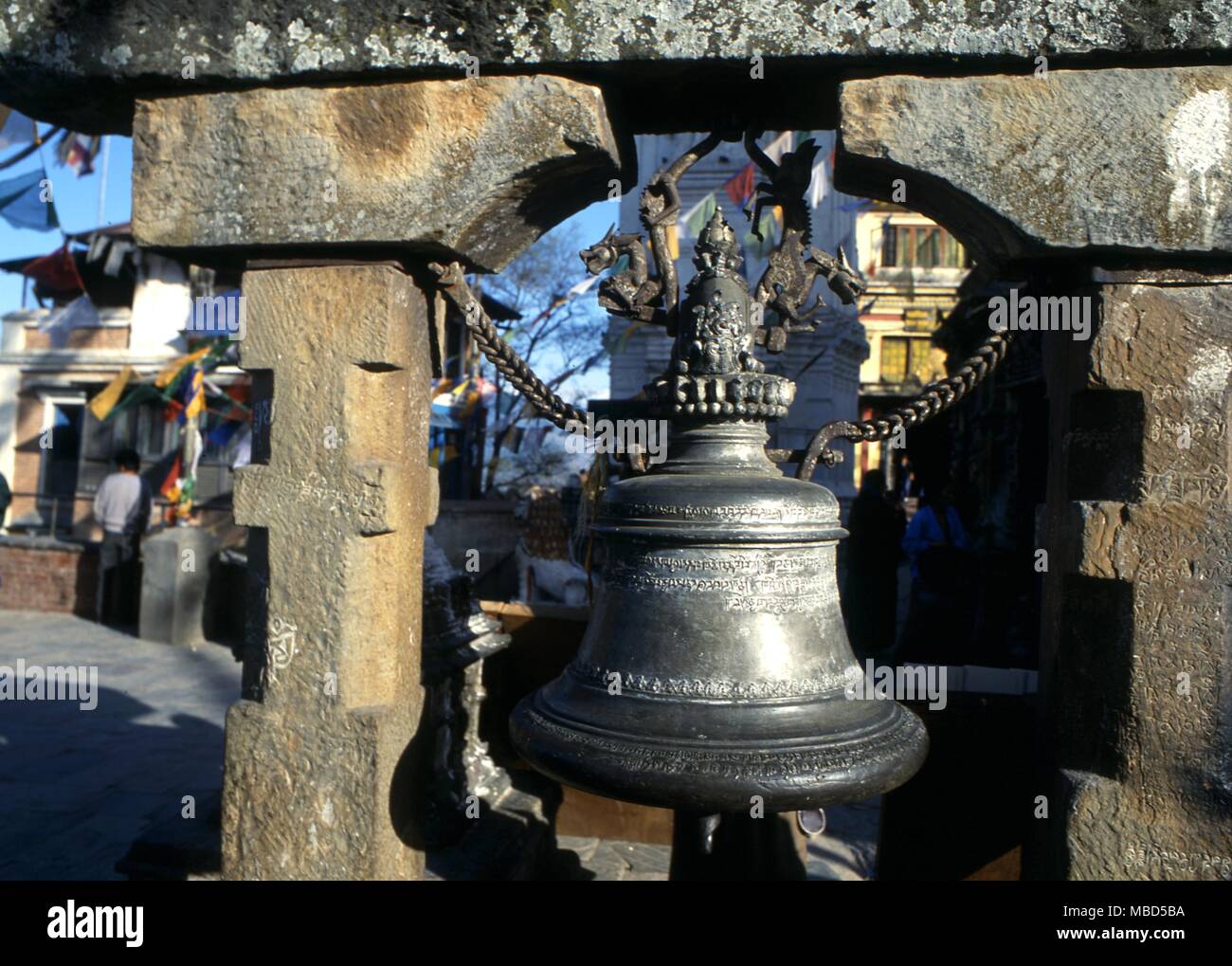 Simboli - Campane campana con un drago progettazione supporto nel Tempio Swayambunath. Kathmandu, Nepal Foto Stock