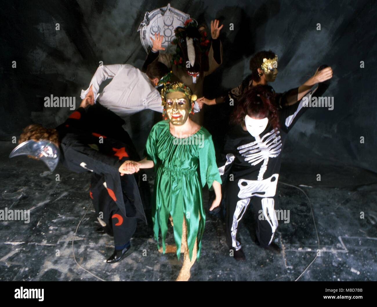 Gruppo di persone in una magia nera/stregoneria burlesque, vestito in costumi stravaganti e maschere, balli all'interno di un cerchio magico. Foto Stock