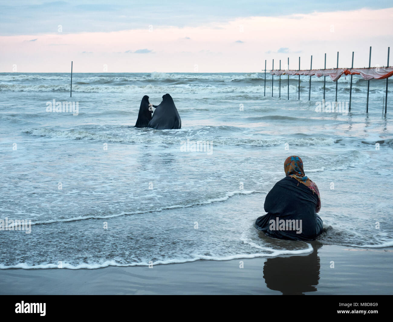 Le donne musulmane di indossare un chador nero godersi le onde sguazzare nel Mar Caspio. Babolsar beach, Iran Foto Stock