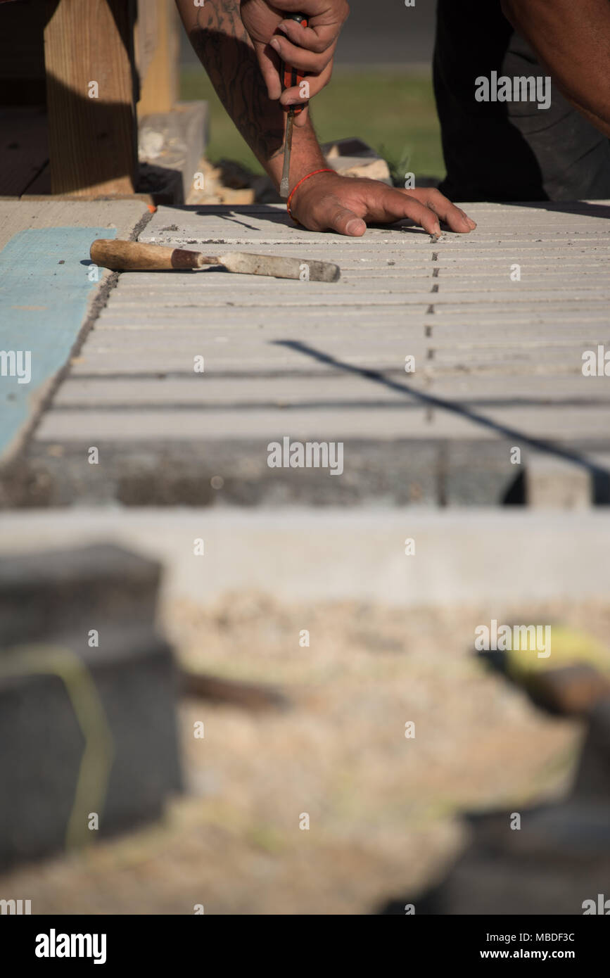 Vista ravvicinata del lavoratore utilizzando strumenti mentre posa mattone su terra Foto Stock