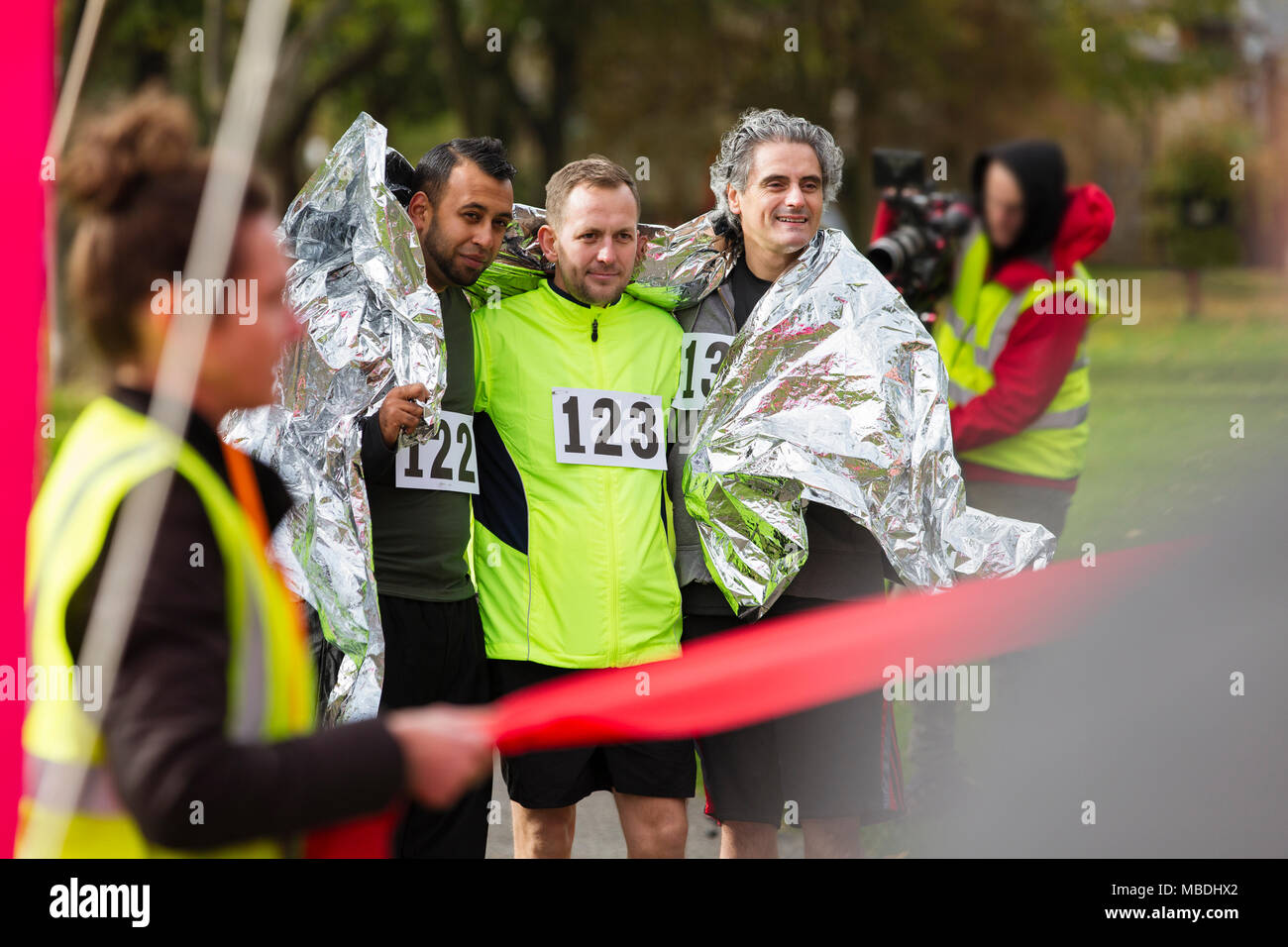 Maschio di corridori della maratona avvolto in una coperta termica al traguardo Foto Stock