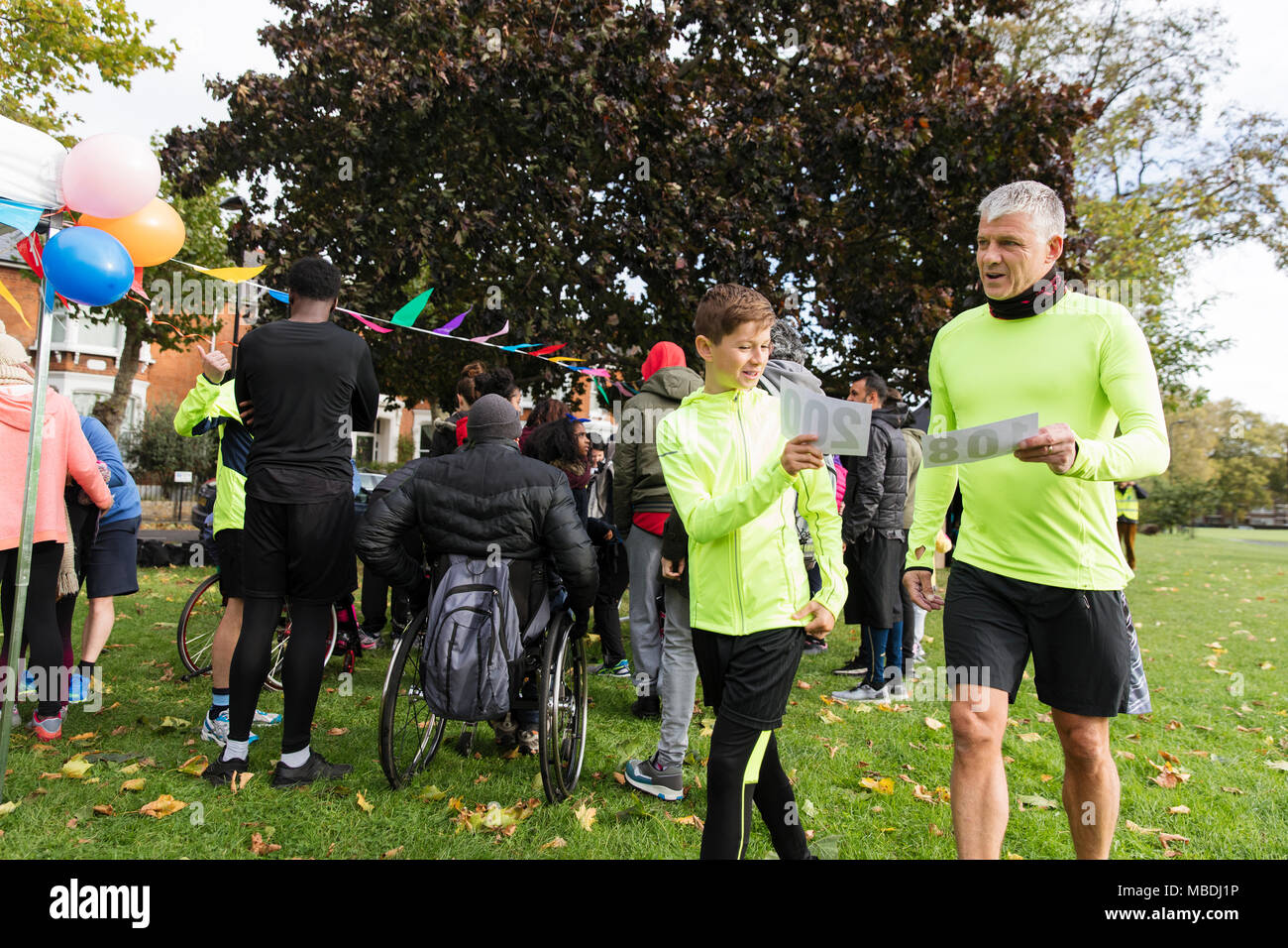 Padre e figlio azienda marathon bibs alla carità eseguire in posizione di parcheggio Foto Stock