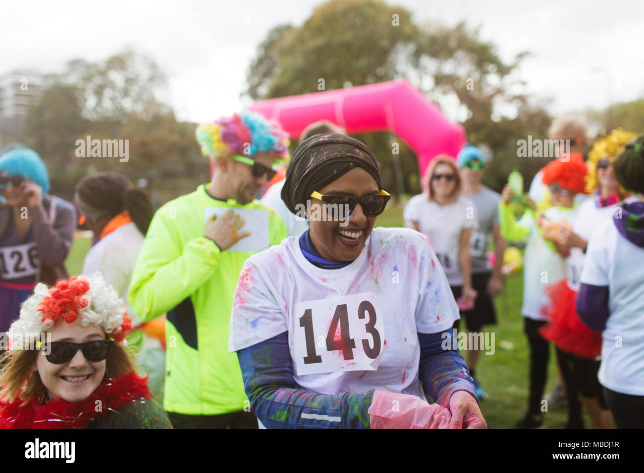 Ridendo femminile coperti in holi polvere ad eseguire la carità in posizione di parcheggio Foto Stock