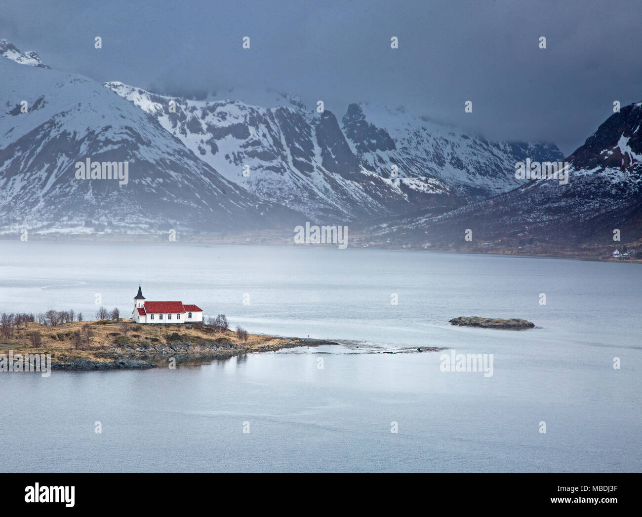 Chiesa remoto lungo il fiordo waterfront sotto le montagne nevose, Sildpoinesnet, Austvagoya, Norvegia Foto Stock