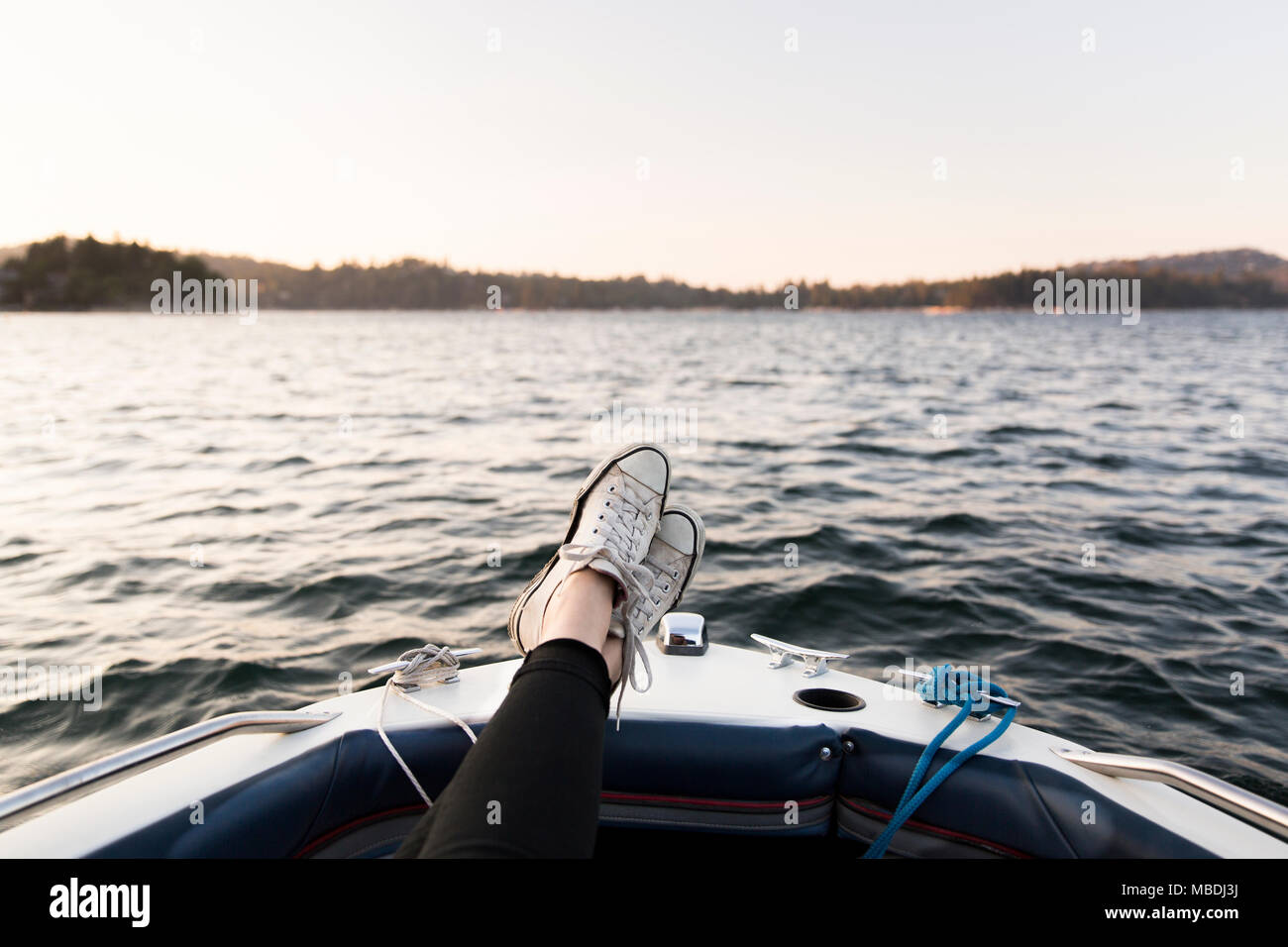 Punto di vista personale donna in barca con i piedi sul tranquillo lago Foto Stock