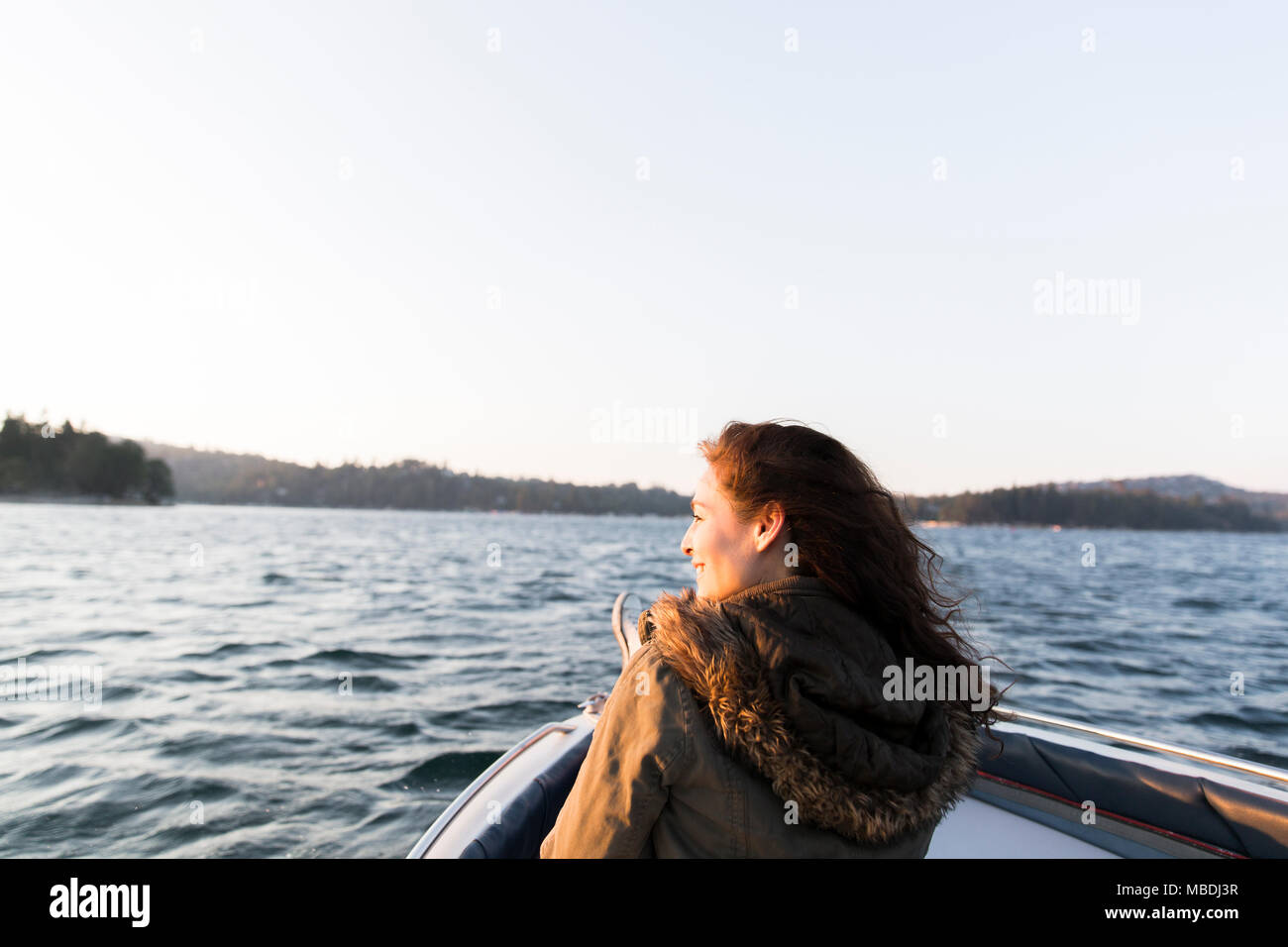 Donna sorridente in barca sul soleggiato e tranquillo lago Foto Stock